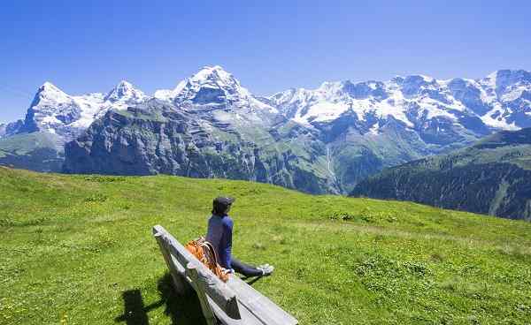 CH-SEEN-ROUTE Traveler siting on the wooden bench looking to beautiful mountain view  Murren  Switzerland shutterstock 495173056